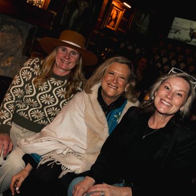 Three guests are seated indoors, smiling warmly.