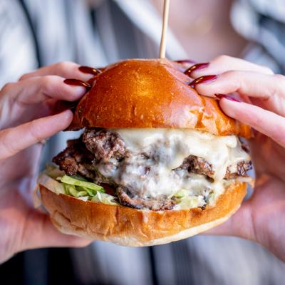 Hands holding a burger.