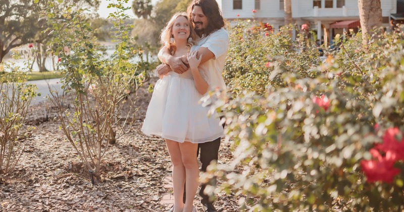 A happy couple hugging in a garden of roses