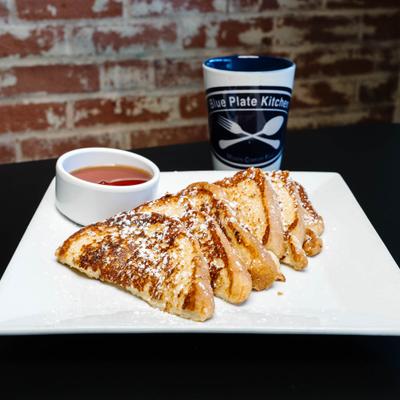French toast dusted with powdered sugar, served with syrup and a coffee mug.