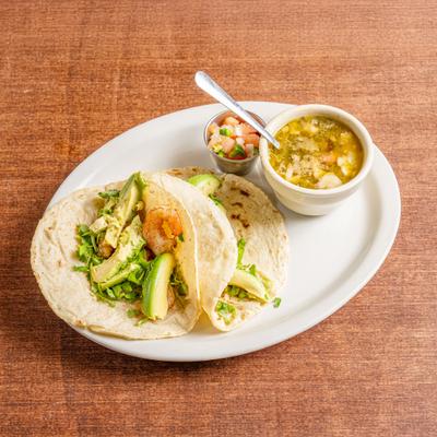 Shrimp tacos with avocado accompanied by pico de gallo and a cup of soup.