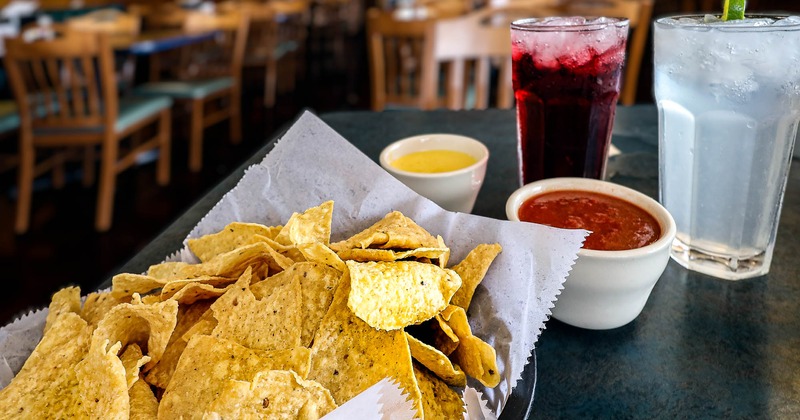 Tortilla chips and salsa dip, with beverages on a table