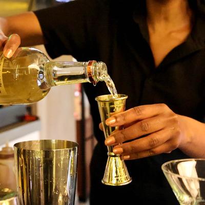 A bartender pouring liquor into a jigger.