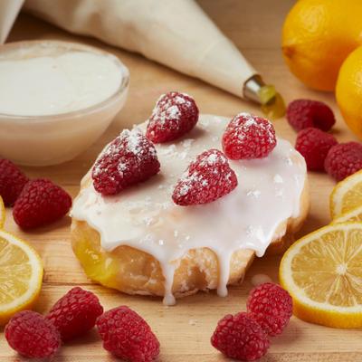 Lemon and raspberry donut topped with raspberries and powdered sugar.