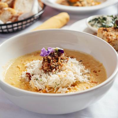 A bowl of soup with rice on a table.
