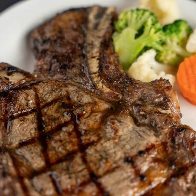 Grilled T-bone steak served with steamed broccoli, cauliflower, and carrot.