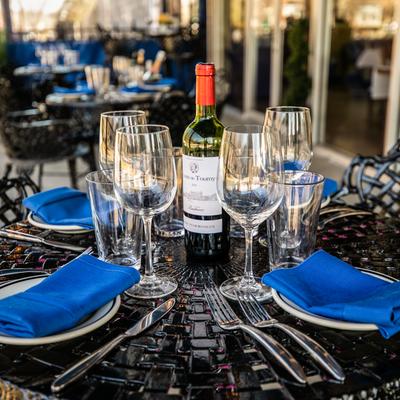 Outside, a table set with tableware and a bottle of wine.