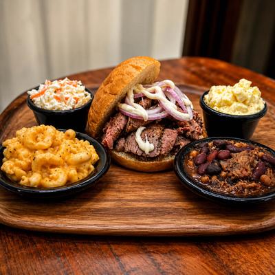 Smoked steak sandwich served with side dishes.