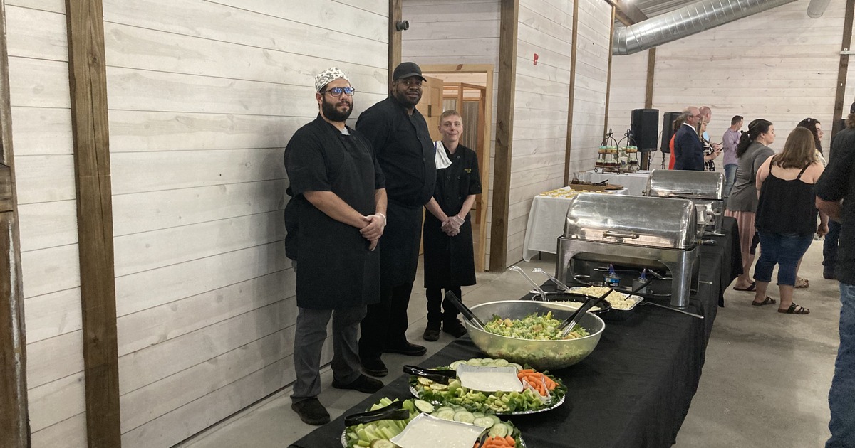 Catering staff standing beside buffet table with food