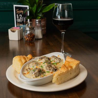 Beef meatballs in a creamy cheese sauce served with bread and red wine.