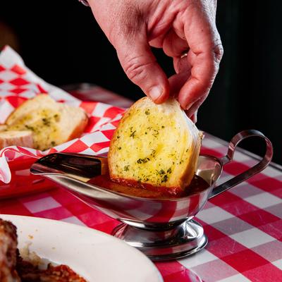 Garlic bread being dipped, hand shot.