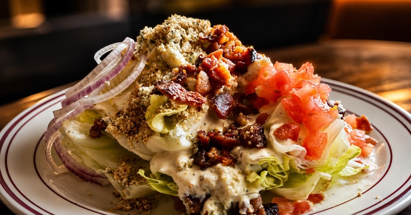 Wedge Salad with tomato, blue cheese, bacon, red onion, and seasoned breadcrumbs
