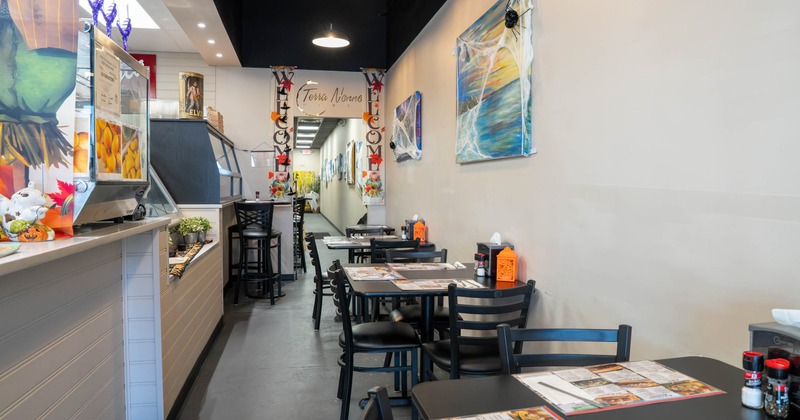 Interior of a modern restaurant with tables, chairs, artwork, and festive decorations