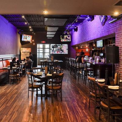 Cozy restaurant interior with wooden floors, brick walls, and warm lighting.