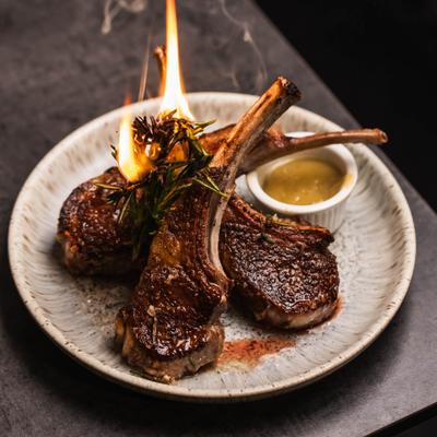Baby lamb chops served with torched herbs and a dipping sauce.