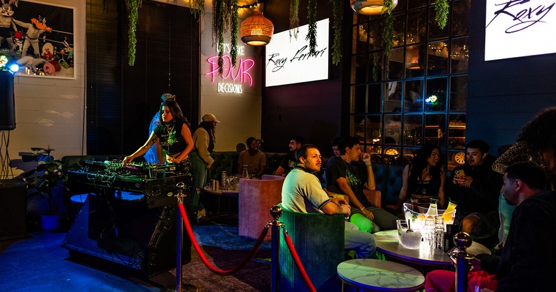 Interior, lounge seating area with guests enjoying music played by a DJ