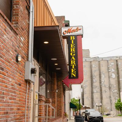 Exterior of the brick building with a sign reading Mac's Biergarten and a backdrop of grain silos.