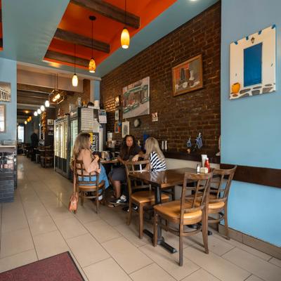 Cozy cafe with brick walls and blue highlights, Three people sit at a wooden table.