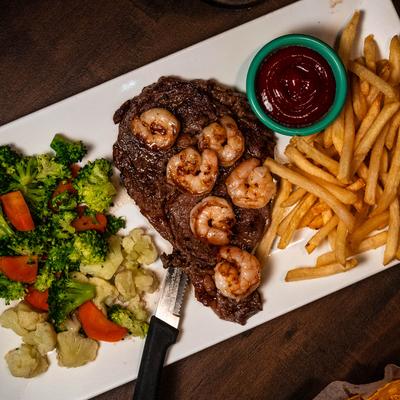 Steak and shrimp with vegetables and fries.