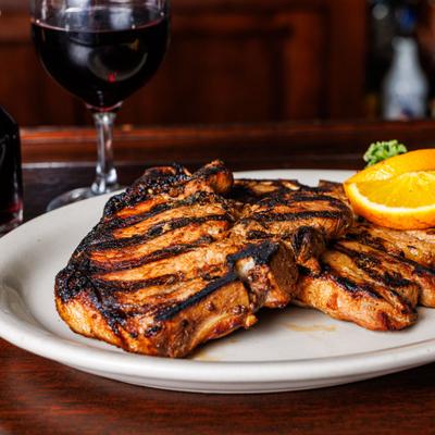 Pork chops with a glass of red vine served on the bar.