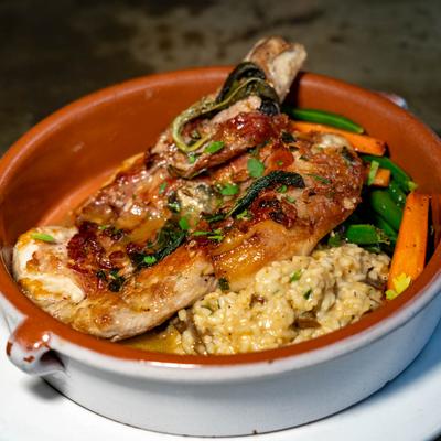 Pork chop saltimbocca served with risotto and green beans in a rustic bowl.