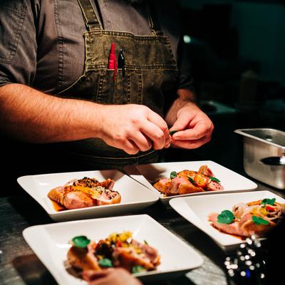 Chef garnishing plated dishes on a counter.