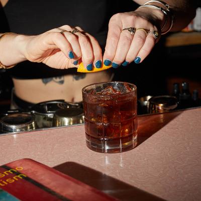 Bartender squeezing lemon juice into a cocktail.