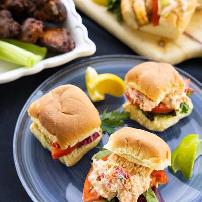 Lobster roll sliders garnished with citrus wedges.