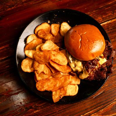 Smash burger with melted cheese, caramelized onions, and potato chips.