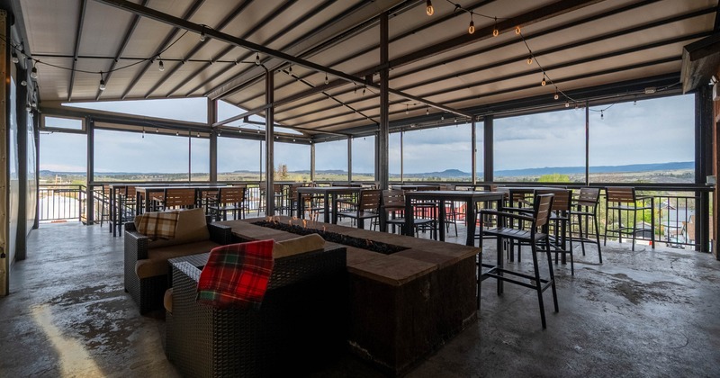 Outdoor patio with a view, featuring high tables, wicker seating, and a fire pit