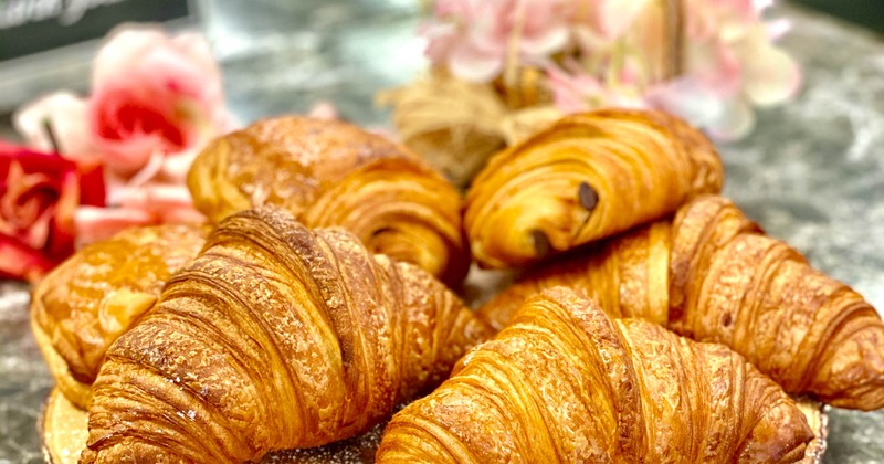 A table with croissants displayed on a round natural wood board