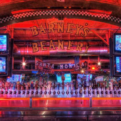 Bar lit with vibrant red and orange neon lights, rows of beer taps are visible