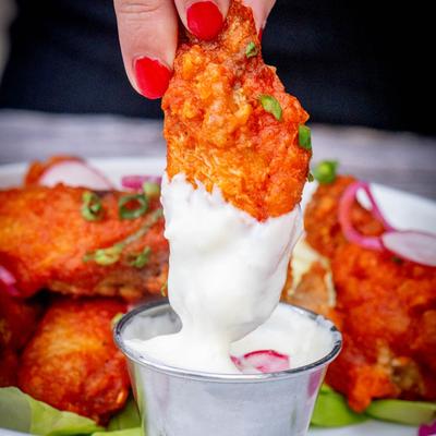 Chicken wings, a wing dipped into a sauce, close up.