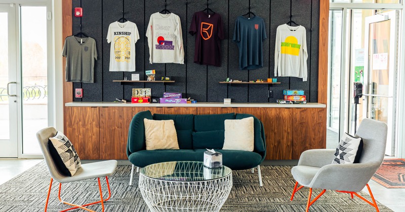 Interior, lounge seating area in front of merchandise wall with hanging T-shirts