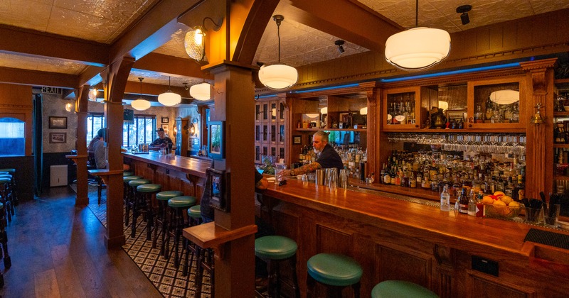 Bar, bar stools, bartender, drink rack behind