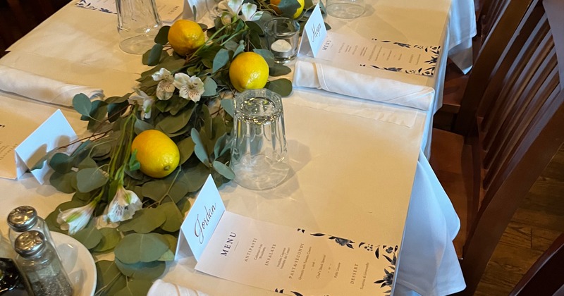 A table covered with a white tablecloth, adorned with fresh lemons and greenery  arranged on top