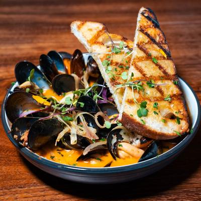 Mussels, in creamy white wine broth, with chili butter, herbs, chorizo, and grilled sourdough.