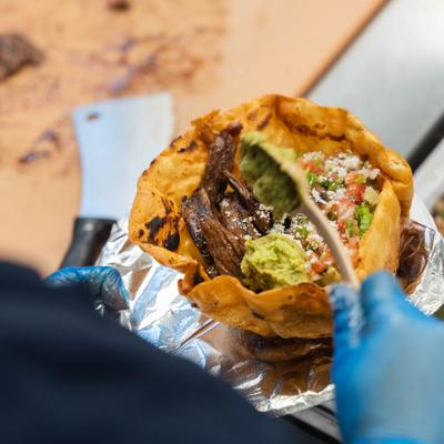 A steak taco salad being served in a crispy tortilla bowl.
