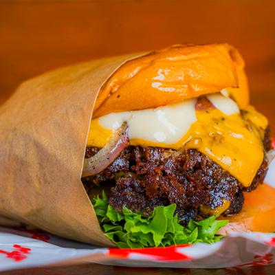 Double Cheeseburger wrapped in paper and served, close-up.