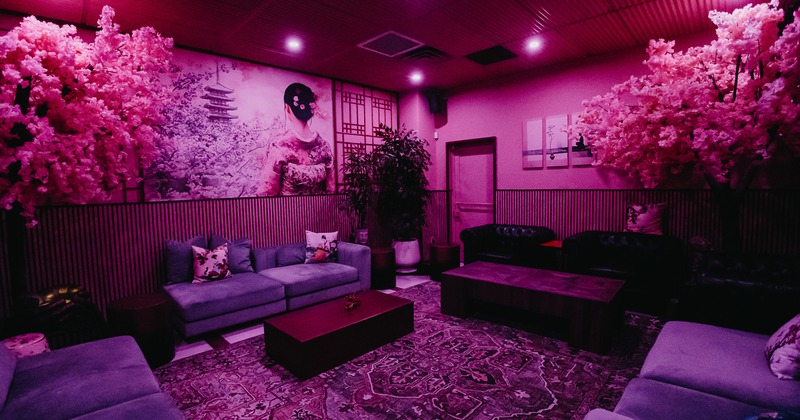 A stylish lounge area with artificial cherry blossom trees, comfortable sofas and leather seating