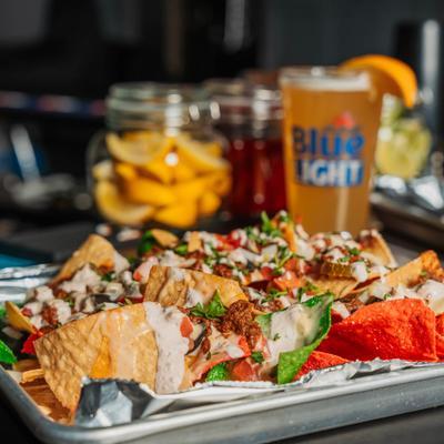 Loaded nachos with a beer in the background.