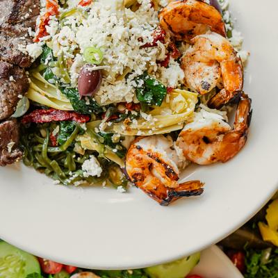 Mediterranean-style pasta featuring grilled shrimp, steak and crumbled cheese.