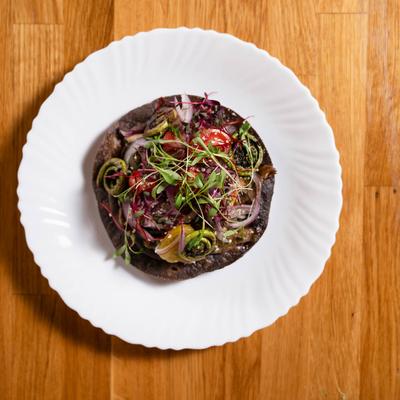 Blue corn tostada topped with sweet potato, beans, summer squash, and chestnut mushrooms.