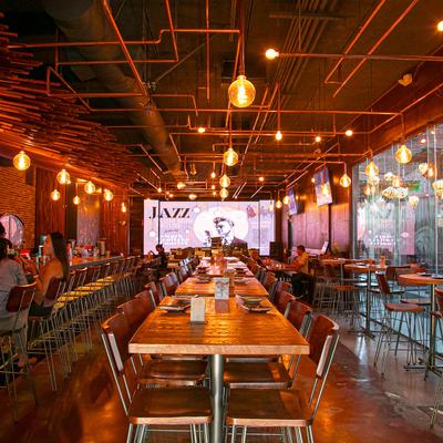 Interior with high and standard seating, TVs, and industrial pipe lighting.