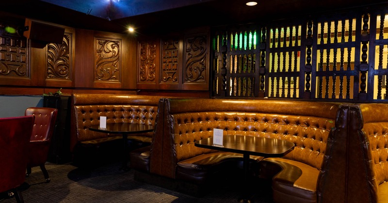 Leather booths and carved wooden wall inside a stylish bar