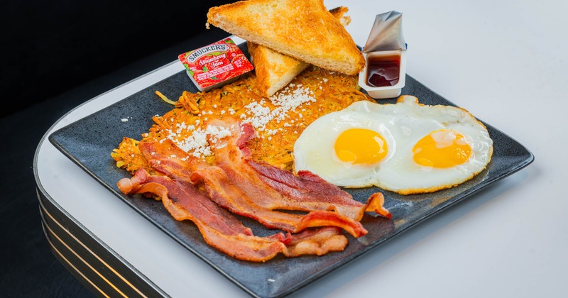 Sunny side up eggs, bacon, hash browns, and toast