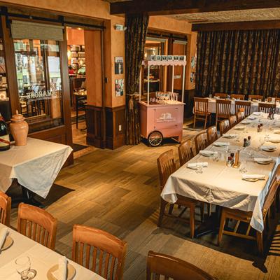 Restaurant interior with set tables and a pink wine cart.