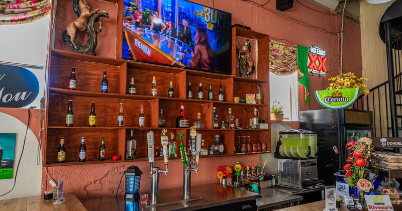 Bar area with wooden shelving, beer taps, and an overhead TV