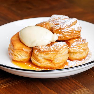 Pastries topped with cream and powdered sugar on a white plate.