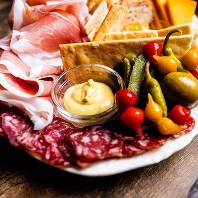 Charcuterie plate with meats, crackers, pickled peppers, and mustard dip.